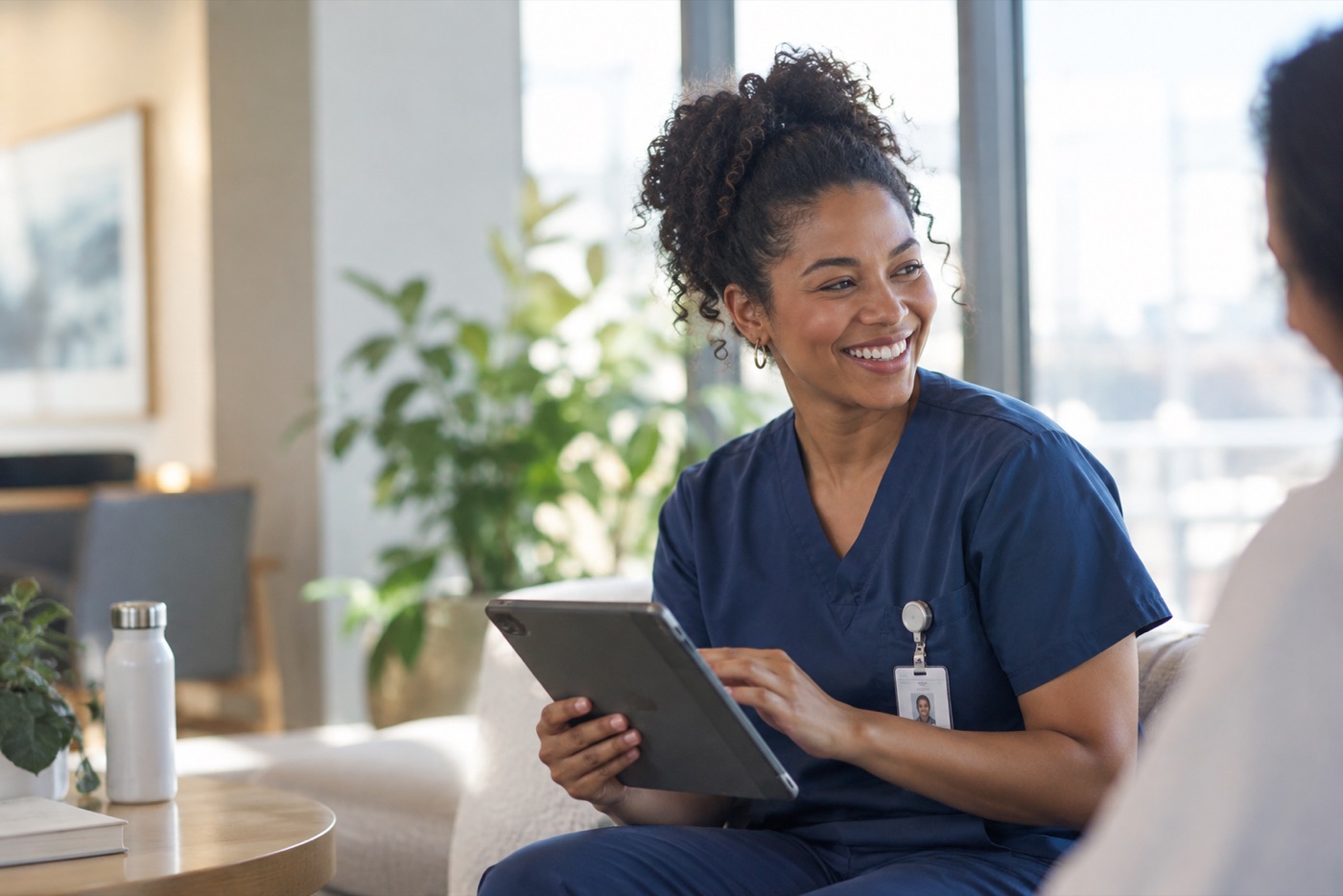 A smiling physician reviewing a tablet in a bright, plant-filled room